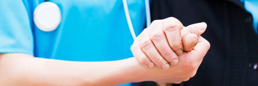 A health care worker holding the hand of a patient