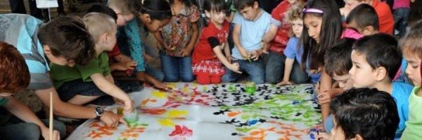 Children from a variety of backgrounds working on a multi-colored diversity mural together