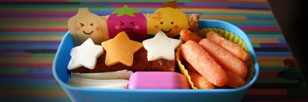 A school lunch packed in a lunch box with some construction paper characters.