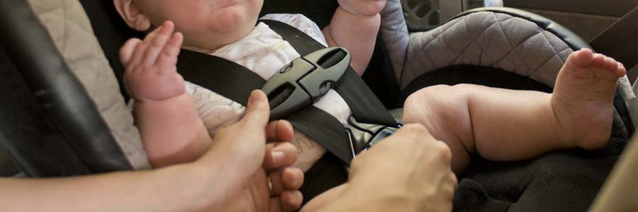 Parent securing baby in car seat