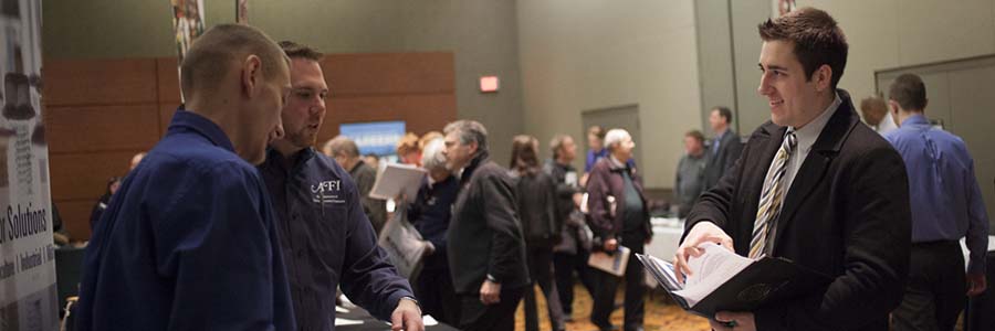 Man talking to men in a booth at a job fair