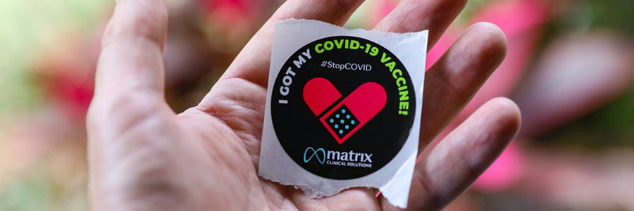 Hand holding a sticker saying "I've got my COVID-19 vaccine