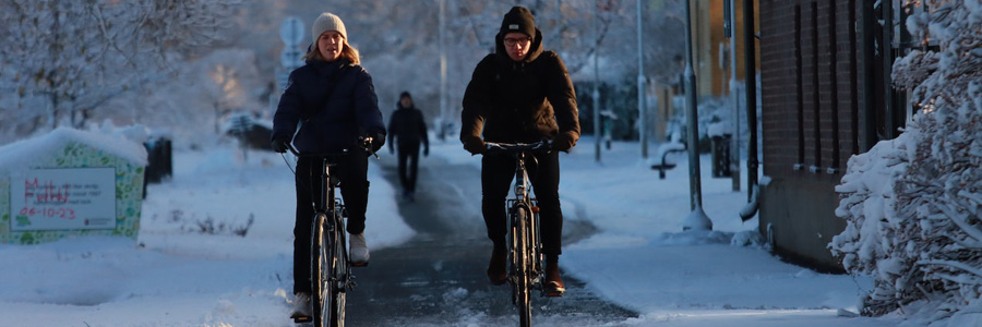 A couple biking through a street in winter