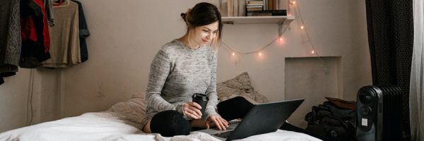 Woman smiling sitting on the bed with laptop