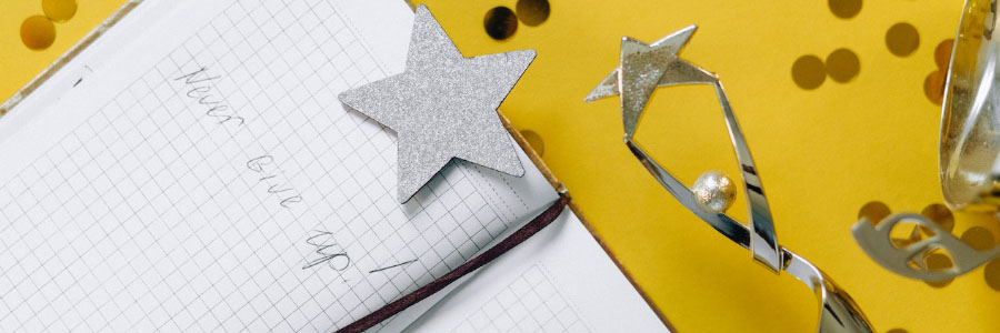 Stars and trophy near notebook with a note saying "never give up!"