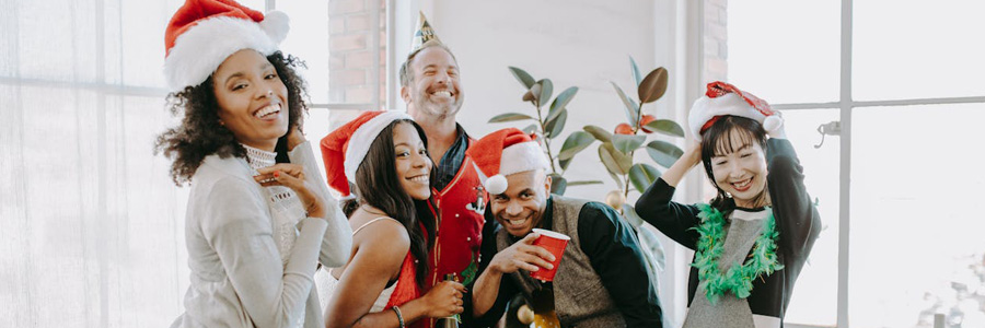A group of friends posing for the camera wearing Santa hats