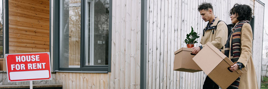 A couple moving some boxes into a house for rent